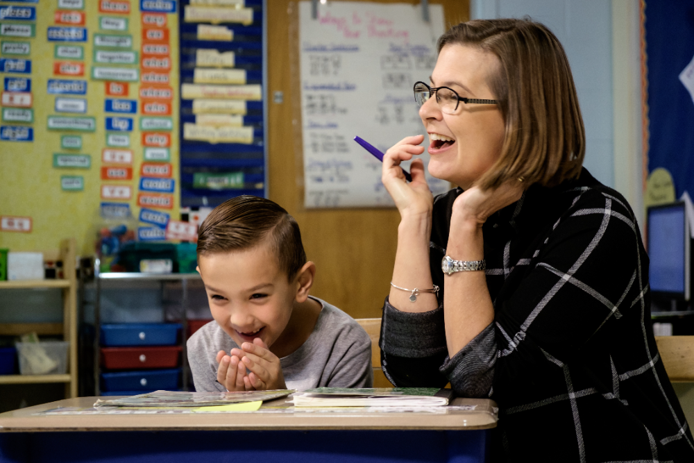 Jan Burkins laughing with a young student during a reading lesson